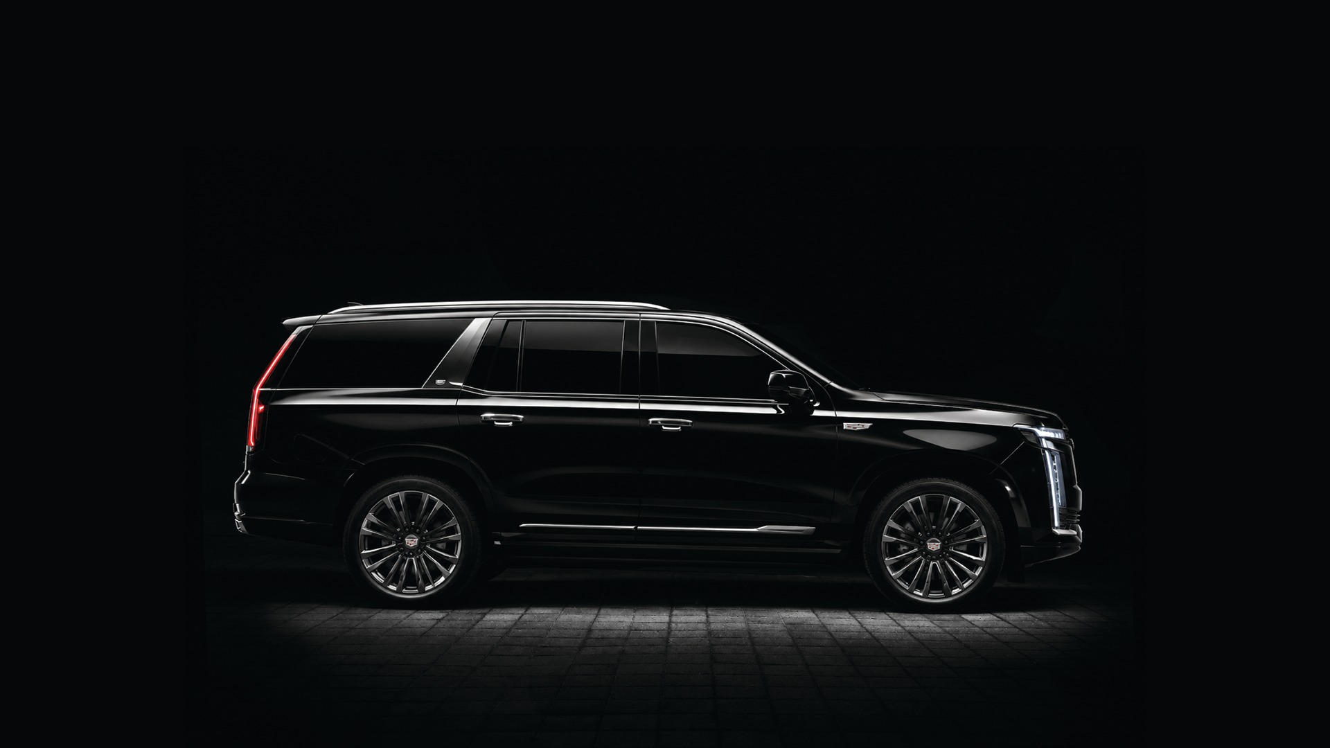 Black Cadillac Escalade in side profile on a black ground